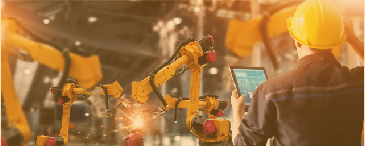 Operatore che con il tablet controlla dei robot industriali in funzione, simbolo di un utilizzatore finale che gestisce impianti automatizzati